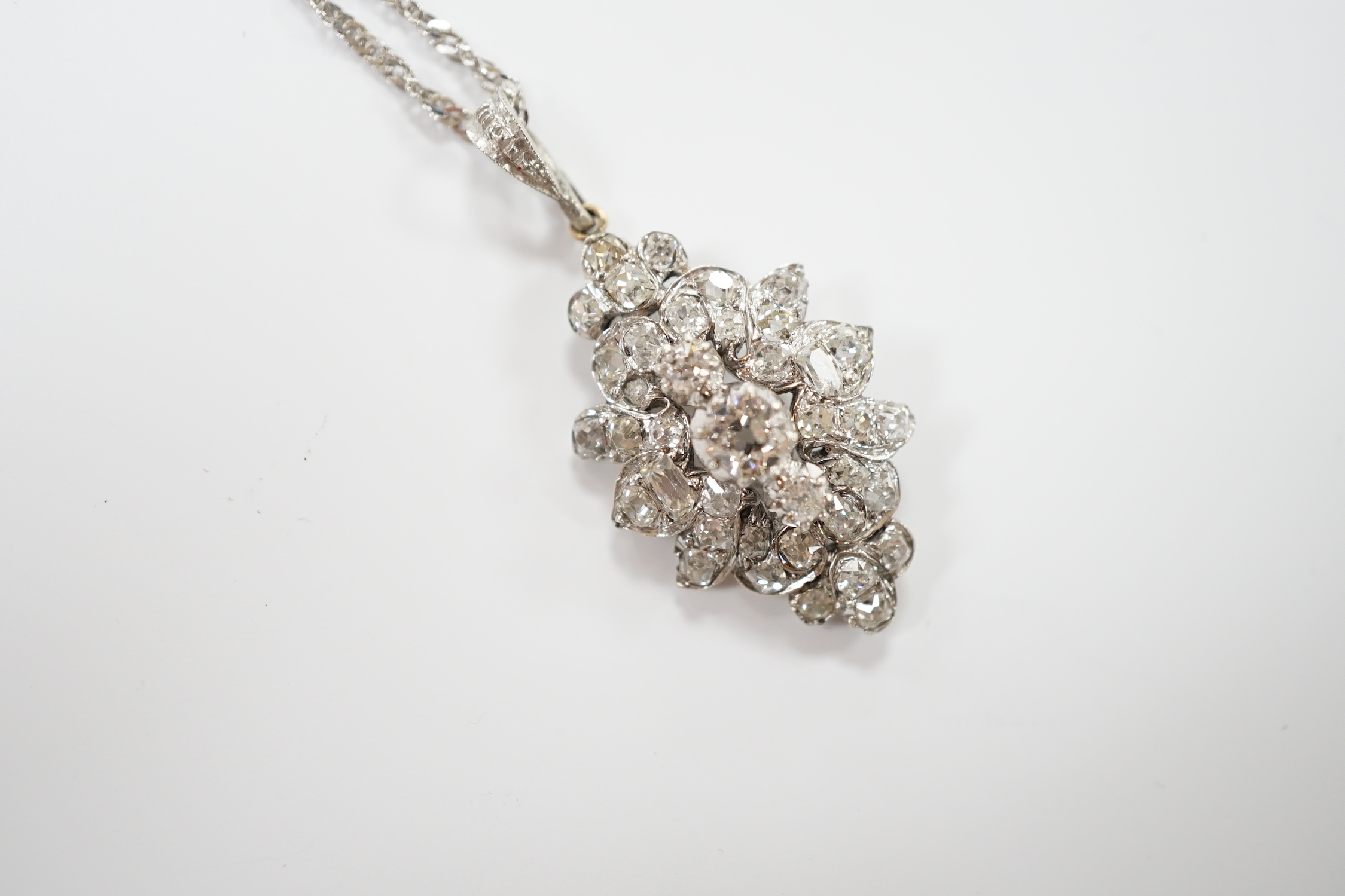 A white metal and diamond cluster set oval pendant, 27mm, on 9kt white metal chain, gross weight 5.8 grams.